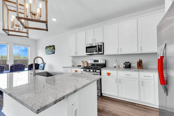 a kitchen with stainless steel appliances granite countertop a sink a stove and cabinets
