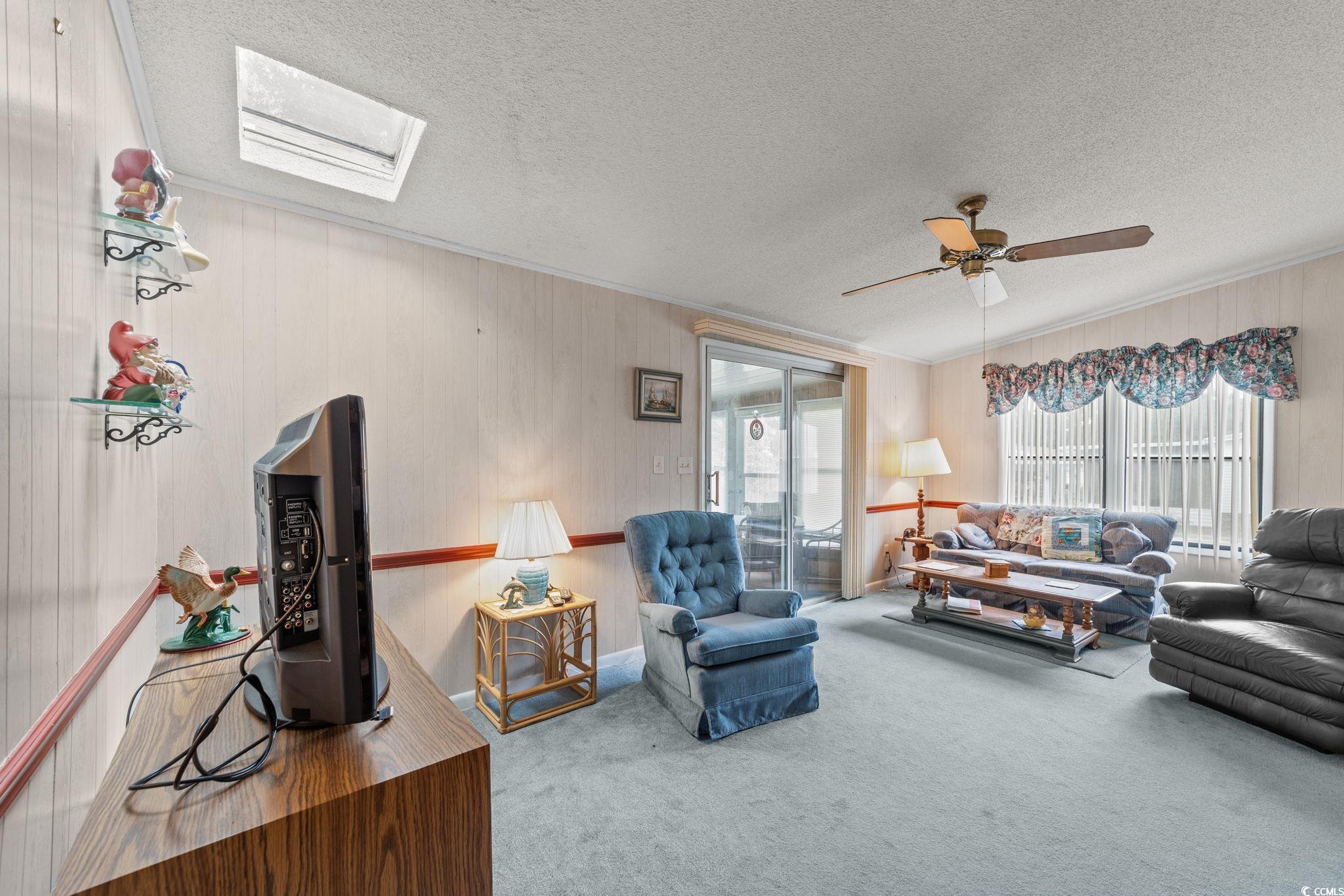 894 South Marlin Circle Murrells Inlet, SC 29576 - Photo 11 of 40 Living area with carpet flooring, a skylight, a textured ceiling, ornamental molding, and wooden walls