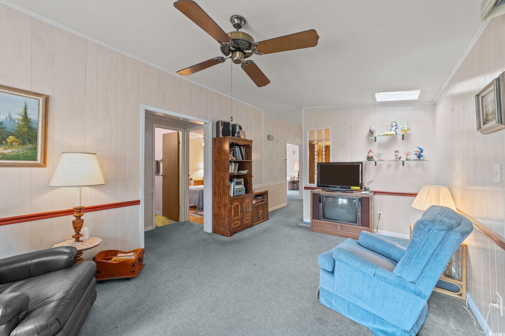 894 South Marlin Circle Murrells Inlet, SC 29576 - Photo 12 of 40 Living area featuring ornamental molding, carpet flooring, ceiling fan, and wooden walls