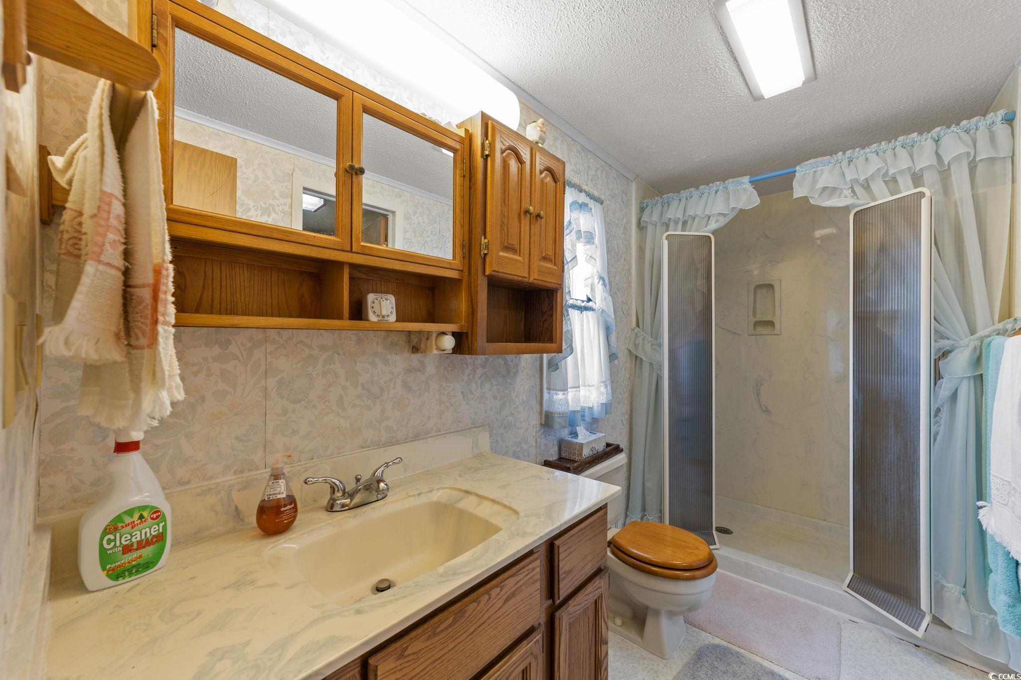 894 South Marlin Circle Murrells Inlet, SC 29576 - Photo 25 of 40 Full bathroom featuring wallpapered walls, vanity, a shower stall, and a textured ceiling