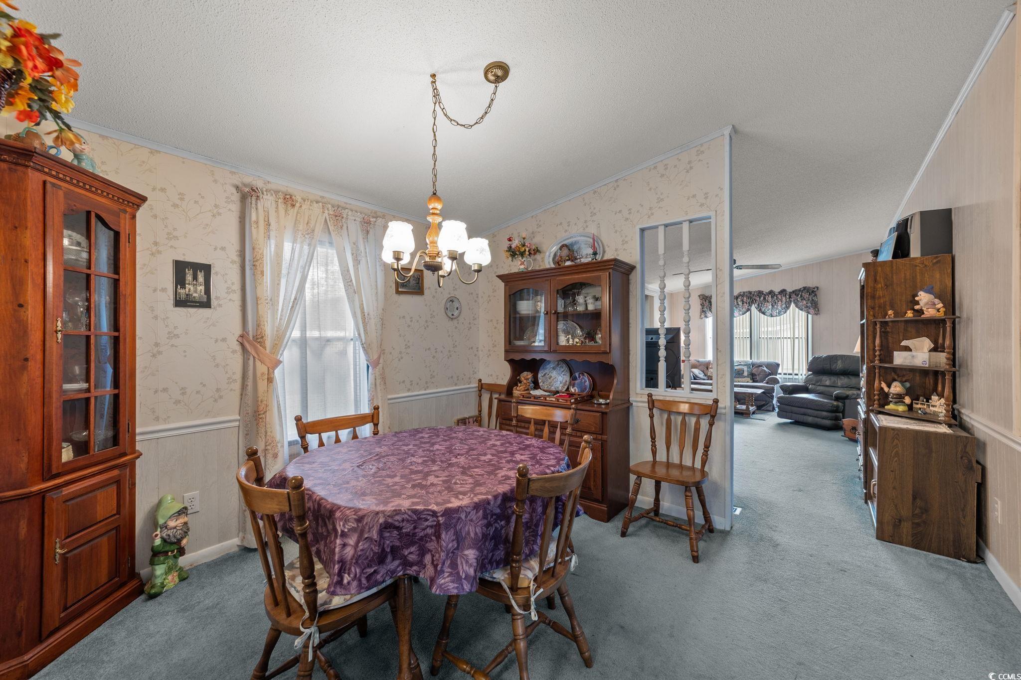894 South Marlin Circle Murrells Inlet, SC 29576 - Photo 10 of 40 Dining room with a wainscoted wall, crown molding, wallpapered walls, carpet flooring, and a chandelier