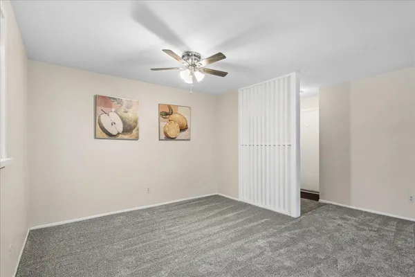 an empty room with windows and fan