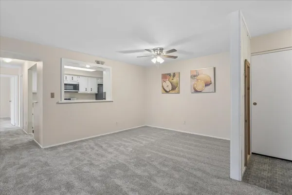 an empty room with windows and ceiling fan