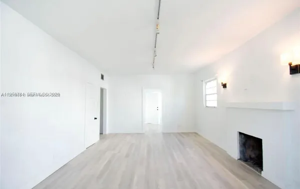 a view of empty room with wooden floor and fireplace