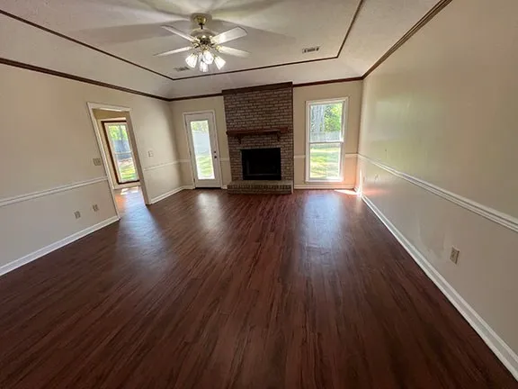 an empty room with wooden floor fireplace and windows
