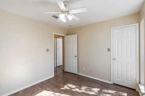 an empty room with windows and chandelier fan