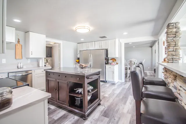 a kitchen with stainless steel appliances granite countertop a kitchen island hardwood floor sink stove dining table and chairs