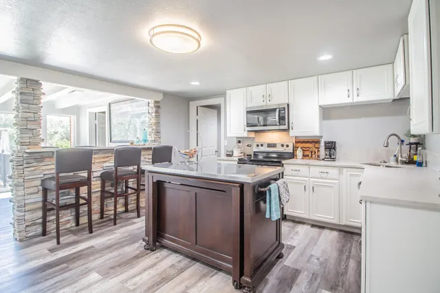 a kitchen with cabinets a sink dishwasher a stove and a refrigerator with wooden floor