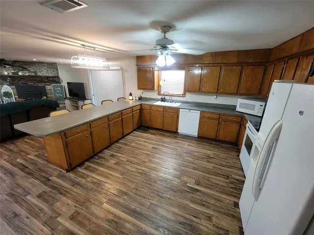 a large kitchen with a large counter top space a sink stainless steel appliances and cabinets