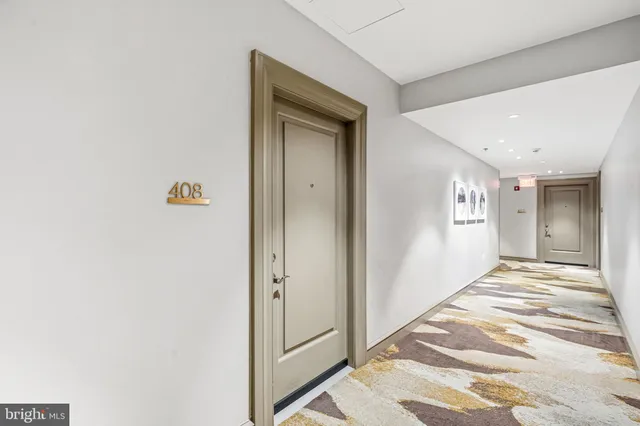 a view of a hallway with wooden floor and a bathroom