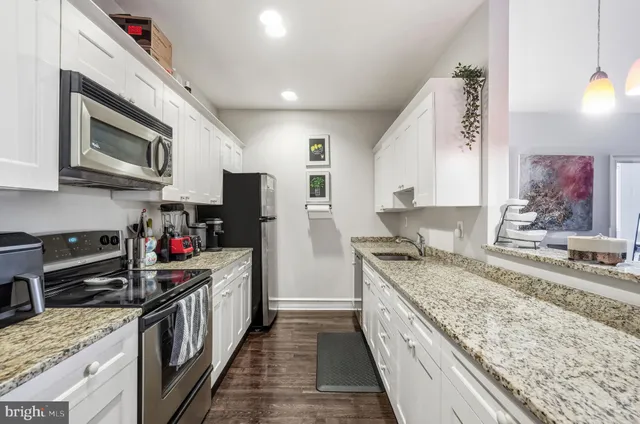 a kitchen with stainless steel appliances granite countertop a stove a sink and a microwave