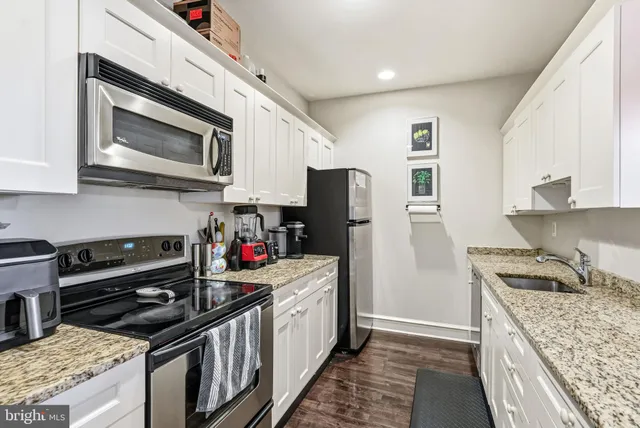 a kitchen with stainless steel appliances granite countertop a stove top oven a refrigerator a sink and dishwasher with wooden floor