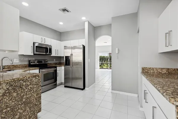 a kitchen with granite countertop a refrigerator and a stove top oven