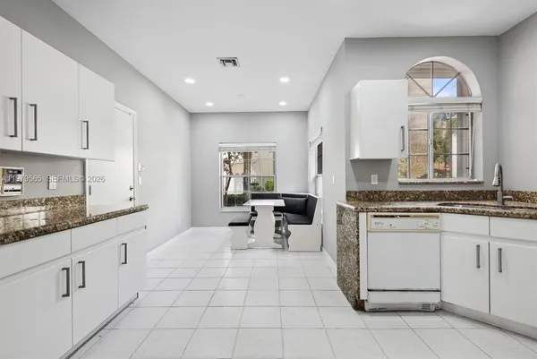 a kitchen with white cabinets and sink