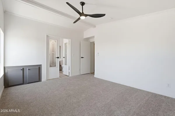 an empty room with a ceiling fan and windows