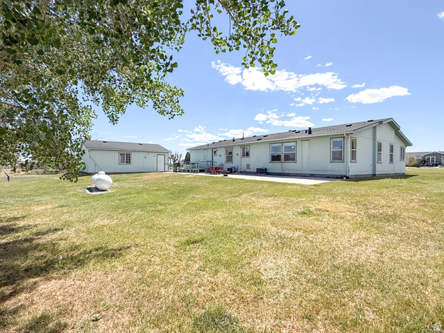 141 South 100 East Emery, UT 84522 - Photo 16 of 17 Spacious property featuring an expansive lawn, a detached storage building, and a rear patio