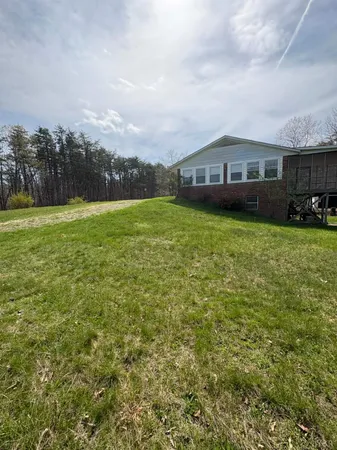 a view of a big house with a big yard and large trees