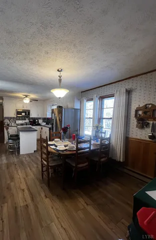 a room with stainless steel appliances kitchen island granite countertop a sink dishwasher a stove and a dining table with wooden floor