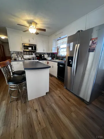 a kitchen with stainless steel appliances a refrigerator a stove a sink dishwasher and a dining table with wooden floor