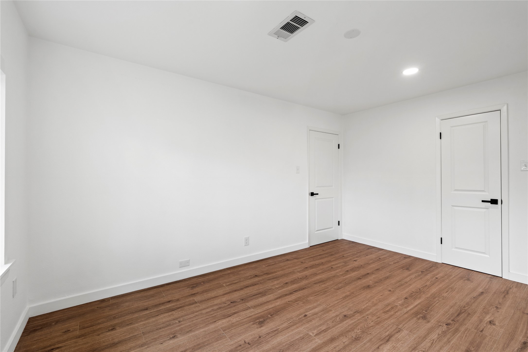 5023 Redstart Street Houston, TX 77035 - Photo 32 of 34 The secondary bedrooms continue the home's cohesive look with neutral walls, warm wide-plank flooring, and sleek black hardware on the doors.
