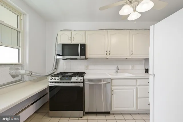 a kitchen with white cabinets and appliances