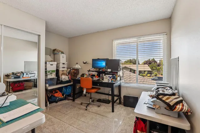 a bedroom with a bed a dresser and a large window