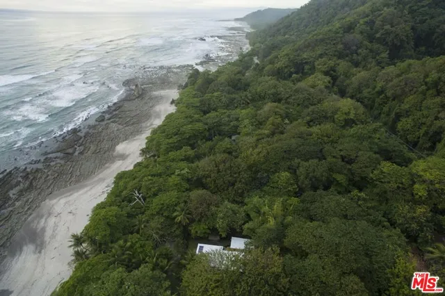 an aerial view of a houses with outdoor space and trees all around
