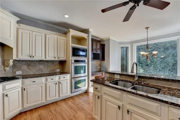 a kitchen with granite countertop a sink a stove and cabinets