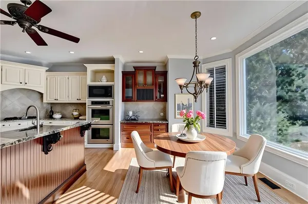 a kitchen with stainless steel appliances granite countertop a dining table chairs a sink and dishwasher a refrigerator with wooden floor