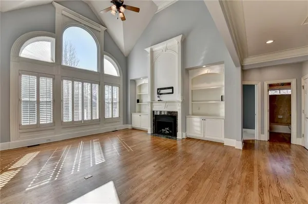 a view of an empty room with wooden floor fireplace and a window
