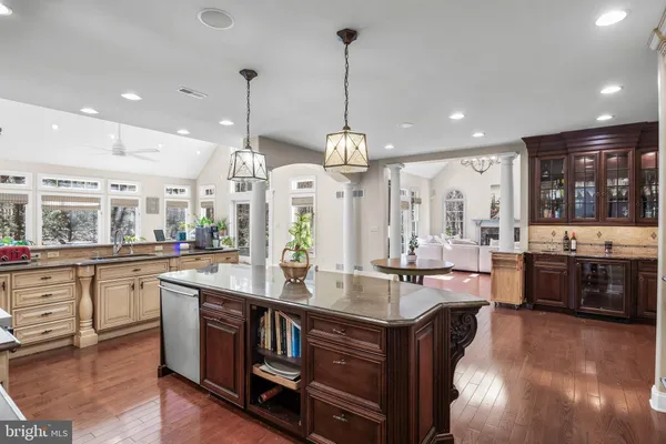 a kitchen with stainless steel appliances kitchen island granite countertop a dining table chairs and white cabinets