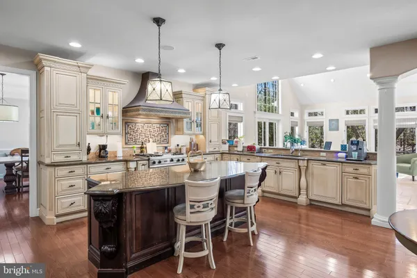 a kitchen with stainless steel appliances granite countertop a stove a sink dishwasher a refrigerator and a dining table with wooden floor