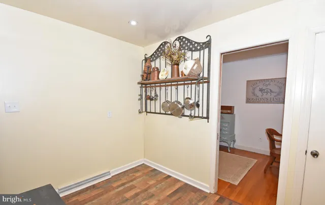 a view of a hallway with wooden floor and a bathroom