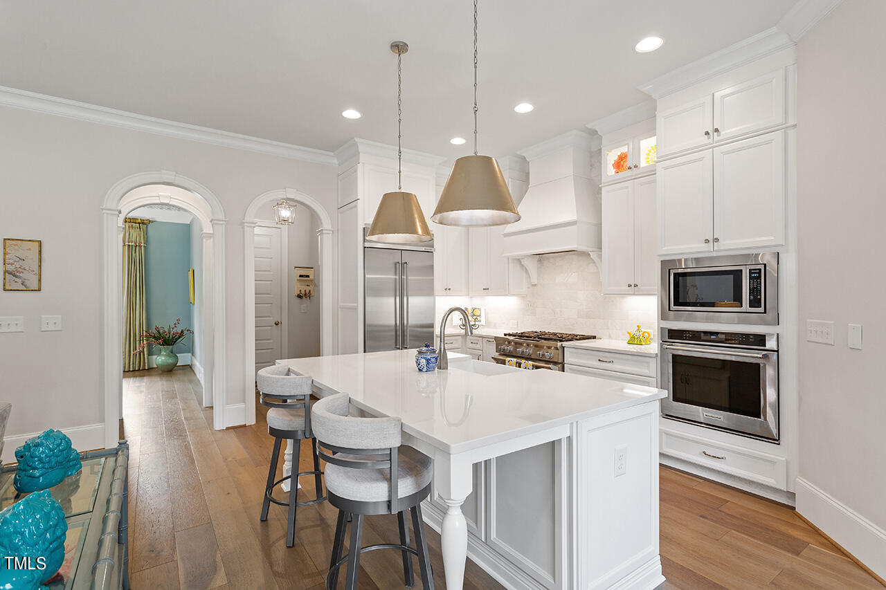 913 Canterbury Road Raleigh, NC 27607 - Photo 12 of 36 a kitchen with stainless steel appliances kitchen island granite countertop a stove a sink a oven a dining table and chairs with wooden floor
