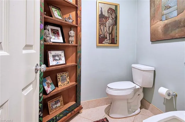 a bathroom with a toilet and a painting on the wall