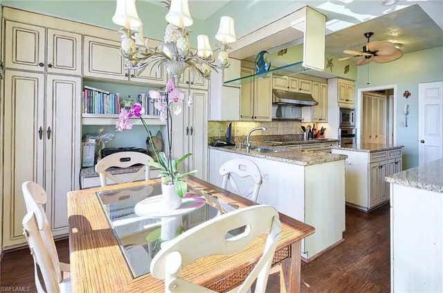 a kitchen with stainless steel appliances granite countertop a sink dishwasher a dining table and chairs with wooden floor