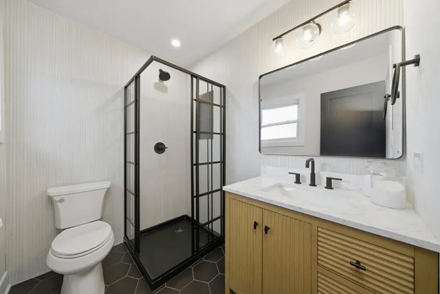a bathroom with a granite countertop toilet sink and mirror