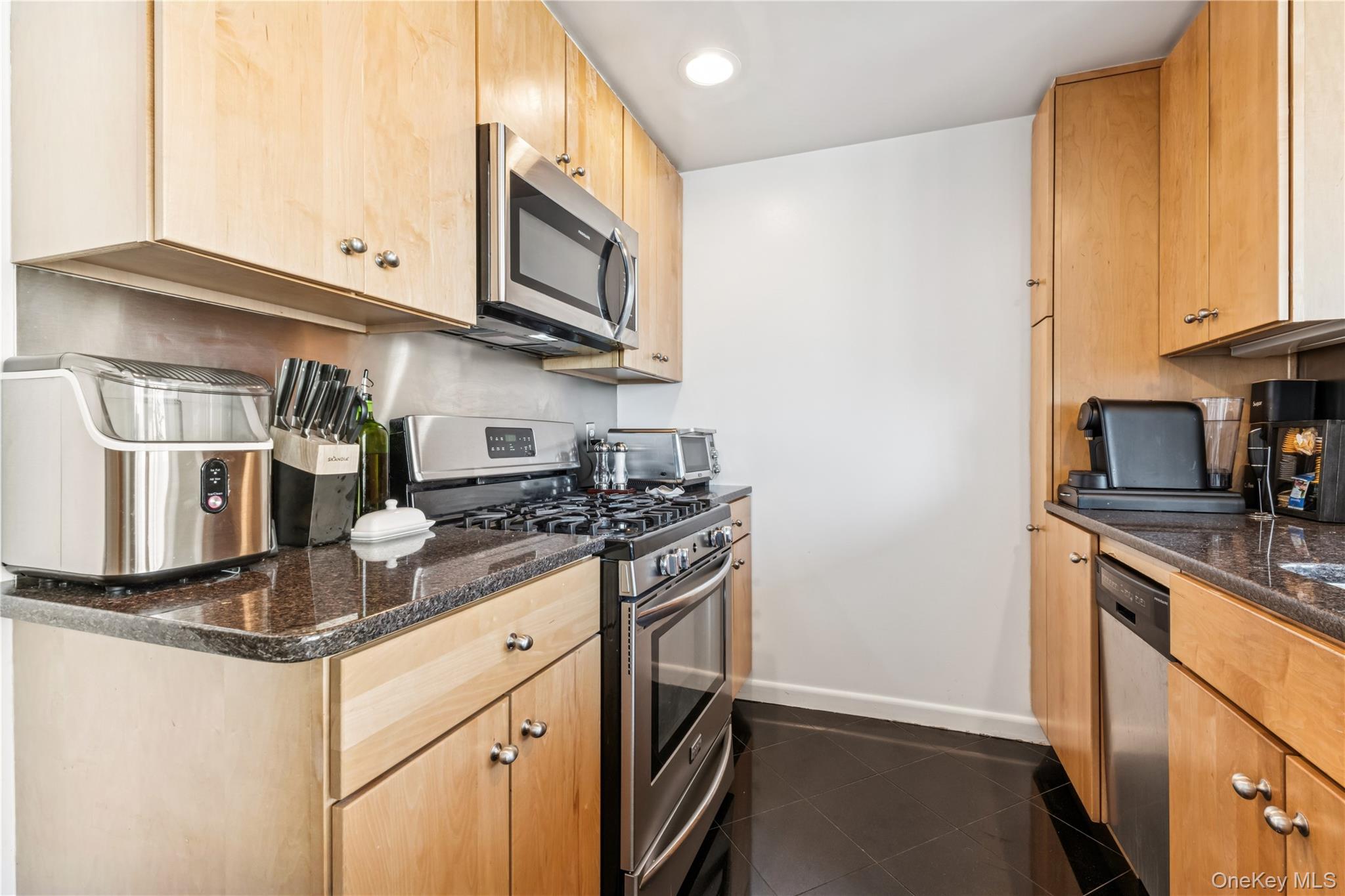4-74 48th Avenue, Unit PH4D Queens, NY 11109 - Photo 5 of 28 a kitchen with stainless steel appliances granite countertop a stove and a microwave