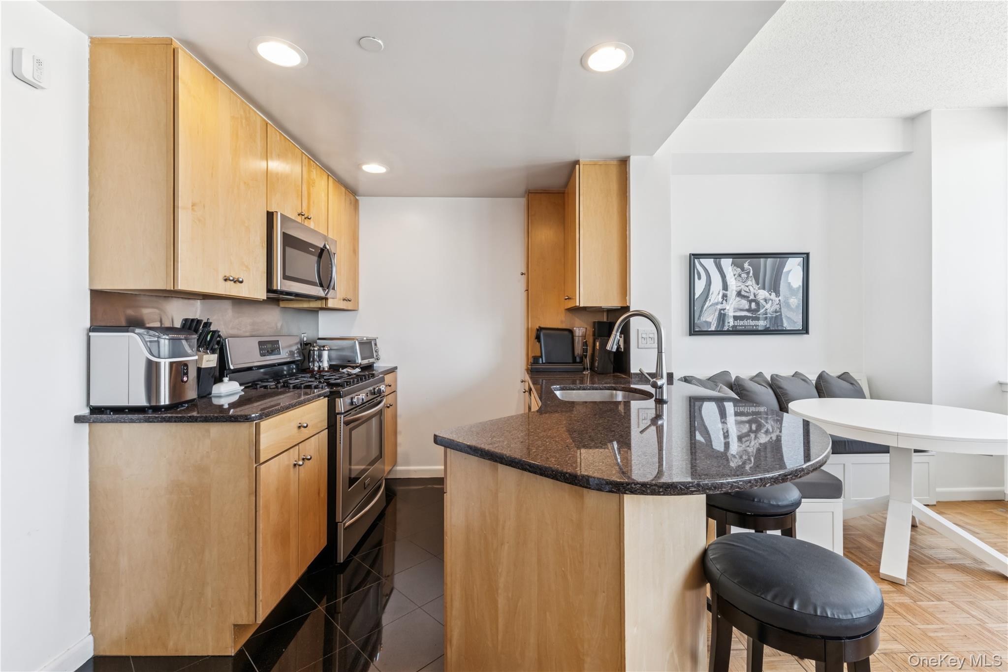 4-74 48th Avenue, Unit PH4D Queens, NY 11109 - Photo 7 of 28 a kitchen with stainless steel appliances granite countertop a sink a stove a microwave a dining table and chairs