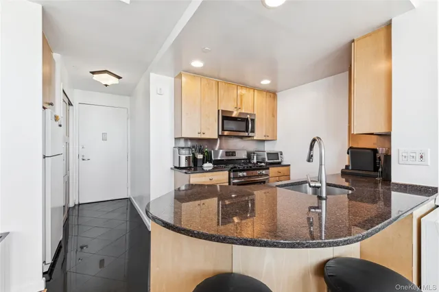 a kitchen with stainless steel appliances granite countertop a sink a stove and a refrigerator