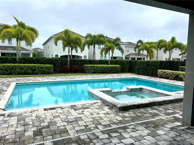 a view of swimming pool with a yard and palm trees