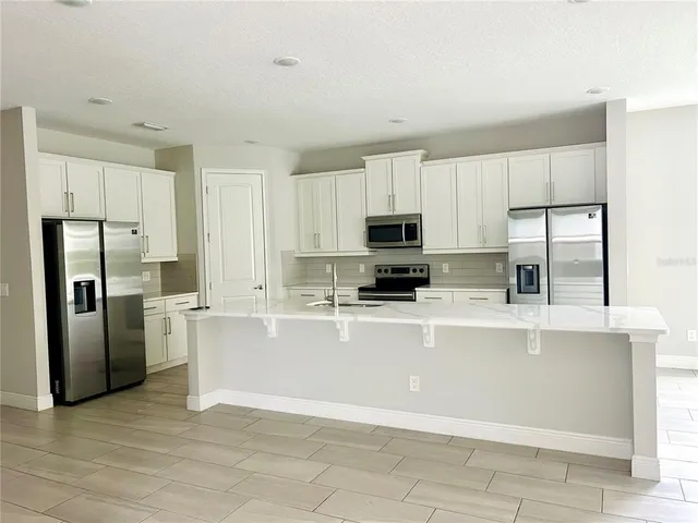 a large kitchen with stainless steel appliances a refrigerator sink a stove a microwave and cabinets