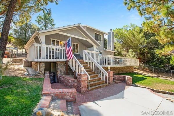 a view of a house with a small yard and a wooden deck