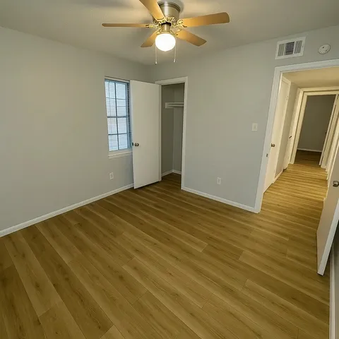 a view of an empty room with a window and wooden floor