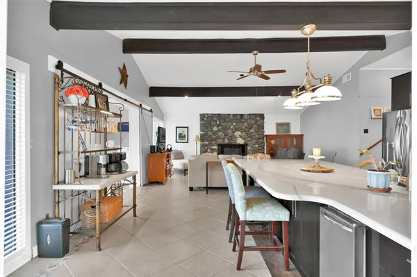 a dining hall with stainless steel appliances kitchen island granite countertop a table chairs and a refrigerator