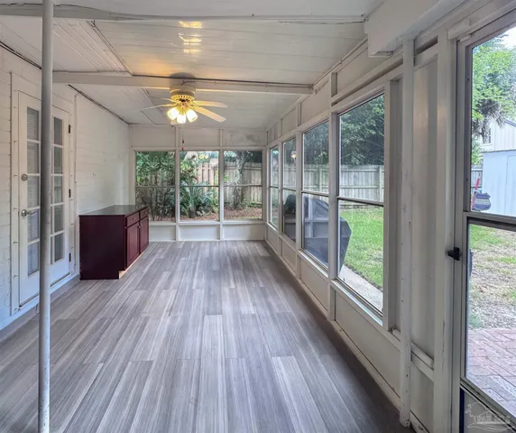 a view of empty room with wooden floor and fan