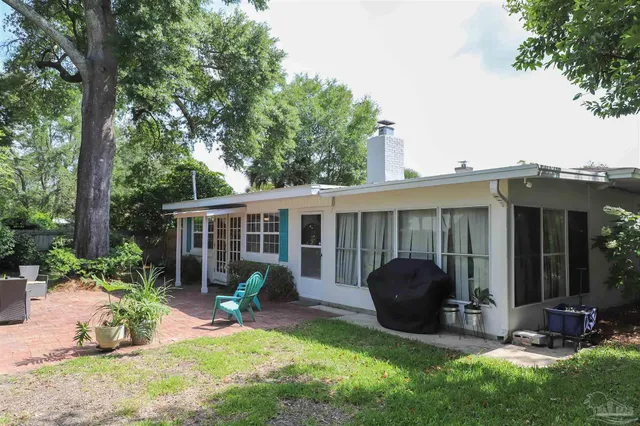 a view of a backyard with table and chairs potted plants and a large tree