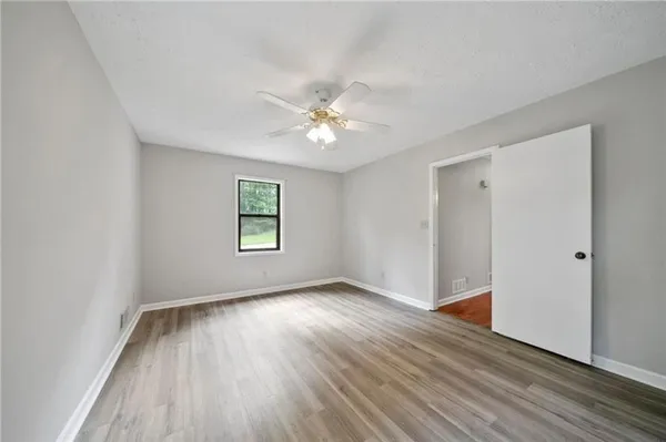 an empty room with wooden floor and a ceiling fan