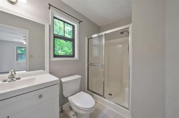 a bathroom with a toilet a sink a mirror and a shower