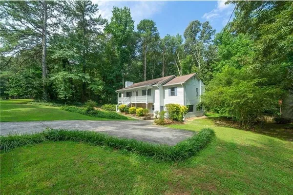 a view of a house with backyard and trees